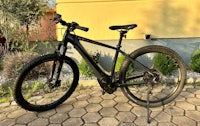 a black electric bike is parked in front of a house