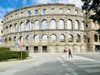 a man is crossing the street in front of an ancient building