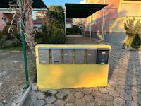 four yellow mailboxes on the side of a street