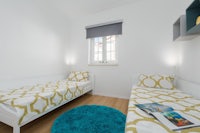 two twin beds in a room with white walls and a blue rug