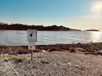 a sign on a beach near a body of water