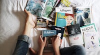 a woman laying on a bed with a lot of magazines